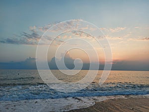 The hot summer sun disappeared behind the clouds of the sea horizon. Blue sky with beautiful clouds on the coast. Summer landscape