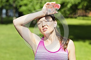 Hot summer weather. girl covering her head from sunshine with hand in pain. young woman with bottle of water from thirst on sun.