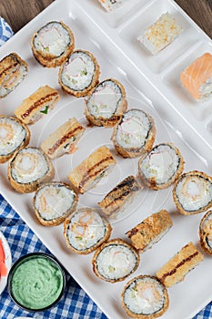 Hot sushi rolls on a white ceramic platter with sauces