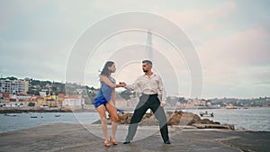 Hot tango dancers moving seductively on gloomy waterfront. Sexy partners dancing