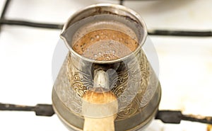 Hot tasty coffee traditionally preparing in old turk on hot cooking stove