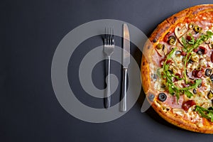 Hot tasty delicious rustic homemade american pizza over black background. Traditional Italian cuisine concept