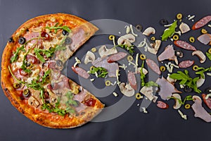 Hot tasty delicious rustic homemade american pizza over black background. Traditional Italian cuisine concept