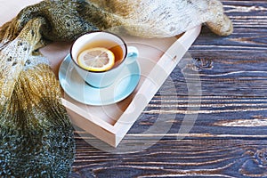 Hot tea and blue cup with lemon on wood background - seasonal relax concept.