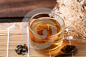 Hot tea in cup glass with dried tea leaves in spoon