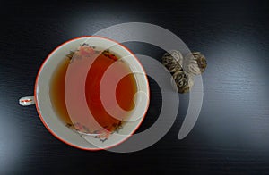 Hot tea cup porselain with tea flowers at a black wooden background/ teatime!