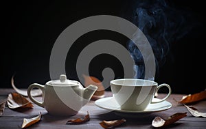 Hot tea cup and teapot on wood background. with steam,