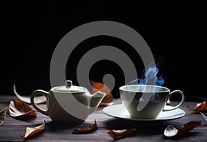 Hot tea cup and teapot on wood background. with steam,