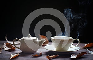 Hot tea cup and teapot on wood background. with steam,