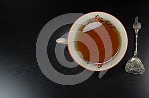 Hot tea cup white porselain with spoon,at black wooden background / teatime