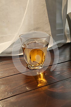 Hot tea cup on wooden table near white curtain window with nature sunlight