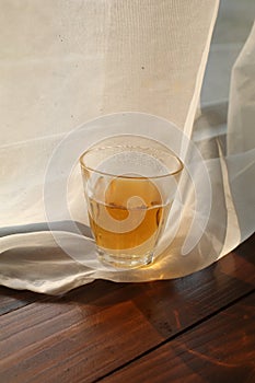 Hot tea cup on wooden table near white curtain window with nature sunlight