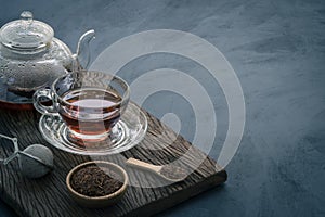 Hot tea in a glass teapot and cup decorated with dried tea leaves