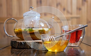 Hot tea in glass teapot and cup with steam on wood background