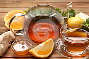 Hot tea, honey, ginger and citruses on wooden table