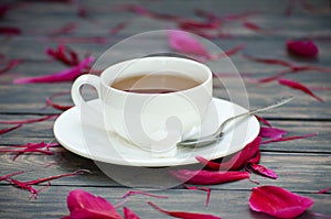Hot tea and peony petals on dark