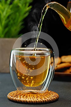 hot tea pouring from teapot into glass cup on table