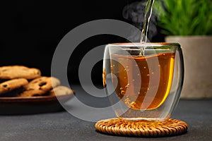 hot tea pouring from teapot into glass cup on table