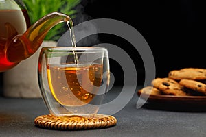 hot tea pouring from teapot into glass cup on table
