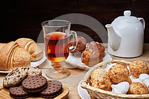 Hot tea put on table, drink breakfast in the morning day, breakfast with croissants and sweets on wooden table