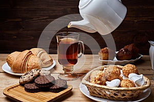 Hot tea put on table, drink breakfast in the morning day, breakfast with croissants and sweets on wooden table