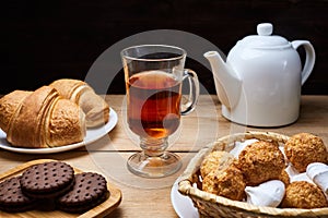 Hot tea put on table, drink breakfast in the morning day, breakfast with croissants and sweets on wooden table