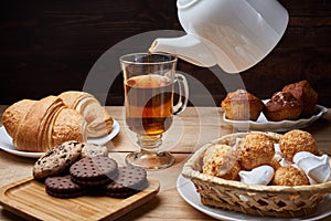 Hot tea put on table, drink breakfast in the morning day, breakfast with croissants and sweets on wooden table