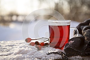 hot tea from rose hips and hibiscus with fruits and a scarf outdoors on a cold winter day, the medical home remedy against flu co