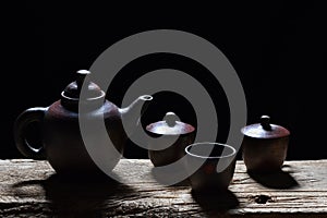 Hot tea in a teapot, glass and cup on a black background.