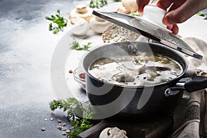 Hot thick mushroom soup with beef, spices and wholegrain barley, meat broth. With black bread, in metal pan, top view, flat lay,