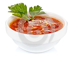 Hot tomato sauce with parsley leaves in a small white ceramic round bowl isolated on white background