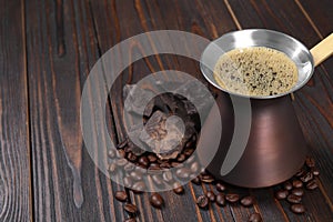 Hot turkish coffee pot, beans and chocolate on wooden table, space for text