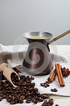 Hot turkish coffee pot, beans and spices on white wooden table