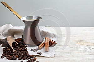 Hot turkish coffee pot, beans and spices on white wooden table, space for text