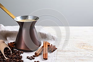 Hot turkish coffee pot, beans and spices on white wooden table, space for text
