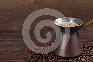 Hot turkish coffee pot and beans on wooden table, space for text