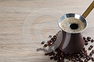 Hot turkish coffee pot and beans on wooden table, space for text