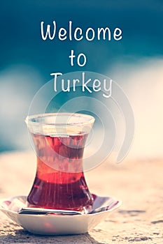 Hot turkish tea outdoors near water. Turkish tea and traditional turkish culture concept. Welcome to Turkey text