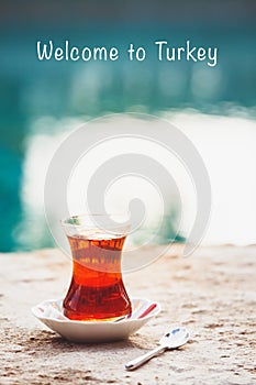 Hot turkish tea outdoors near water. Turkish tea and traditional turkish culture concept. Welcome to Turkey text