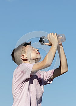 Hot weather, summer heat concept. Child boy dousing or splashing water on face on hot summer day. Heat stroke, sunstroke photo