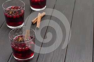 Hot winter drink with cranberries and spices. Star anise and cinnamon sticks on table