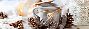 Hot winter drink: hot chocolate in grey mug. Christmas time. Cozy home atmosphere, candle and knitted scarf on background. Cotton