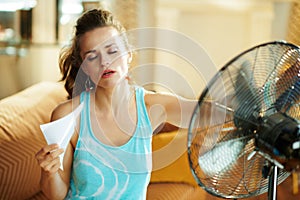 Hot woman in front of working fan suffering from summer heat