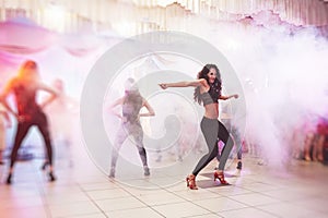 Hot women latin dancer show the performance in a full people lounge, beautiful light and smoke