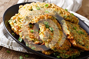 Hot Zucchini Fritters with green onions on a plate close-up. horizontal