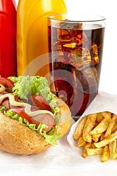 Hotdog with french fries on napkin with glass of cola