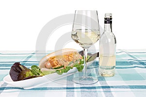 Hotdog on a plate with salad decorated with a glass and a bottle