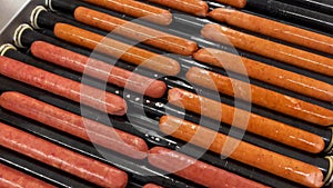 Hotdog sausages getting fried on a rolling hot grill