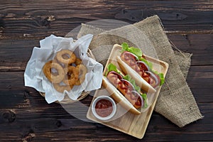 Hotdogs and fried onion rings, beautifully arranged, appetizing on the brown wood dining table