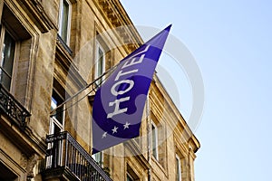 Hotel blue flag sign text three stars in wall building facade in french tourist city